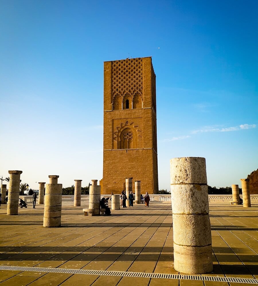 a large stone tower with Hassan Tower in the background